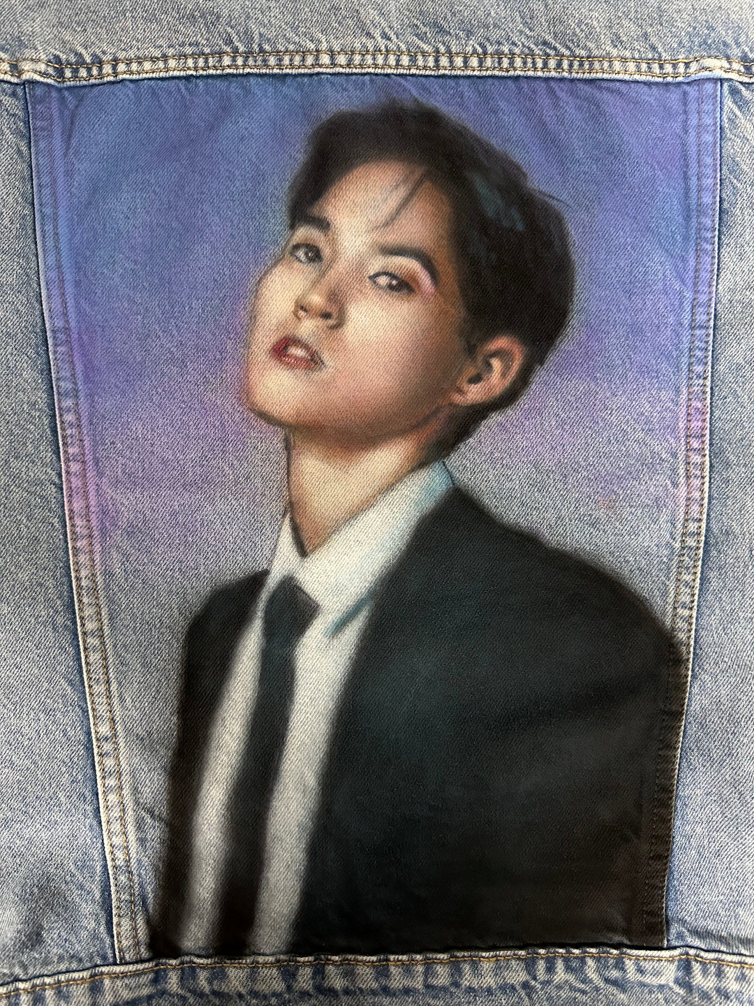 Close-up detail of hand-painted Woosung portrait on denim jacket